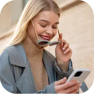 User holding a phone while managing trades on the go with Deriv