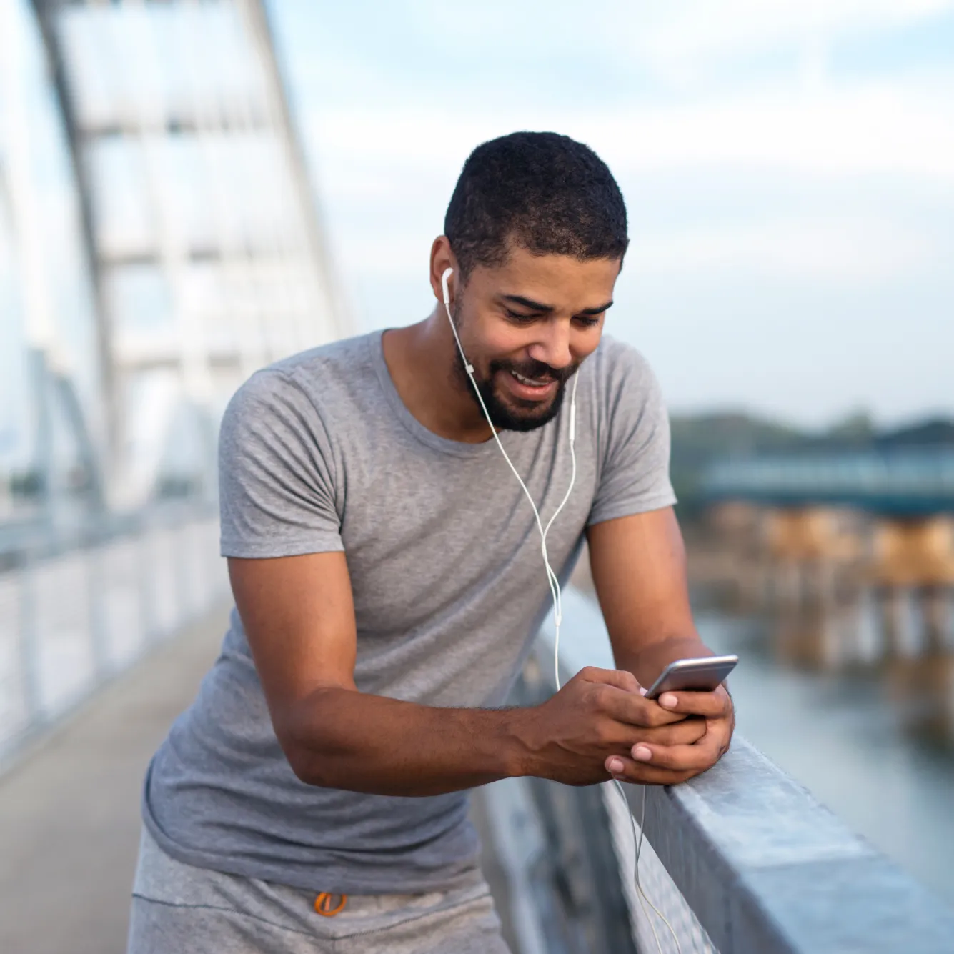 Trader using mobile phone to trade Volatility Indices on Deriv platforms while outdoors